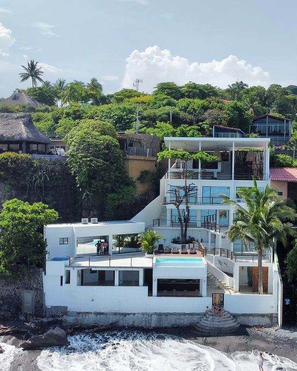 La Ola from the water, white building on the rocks with the pool deck facing the break