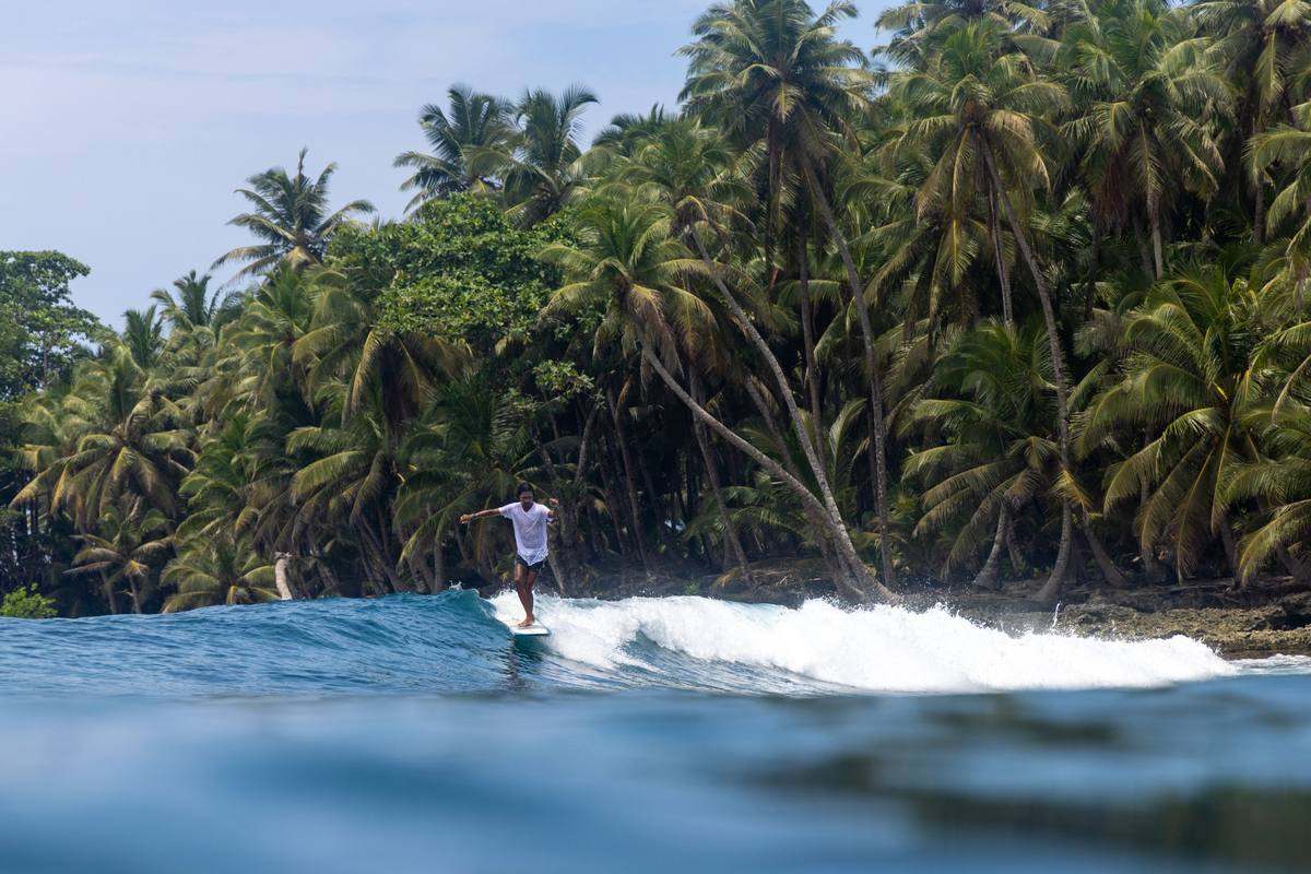A longboarder in a white shirt walking the board on a Mentawais right